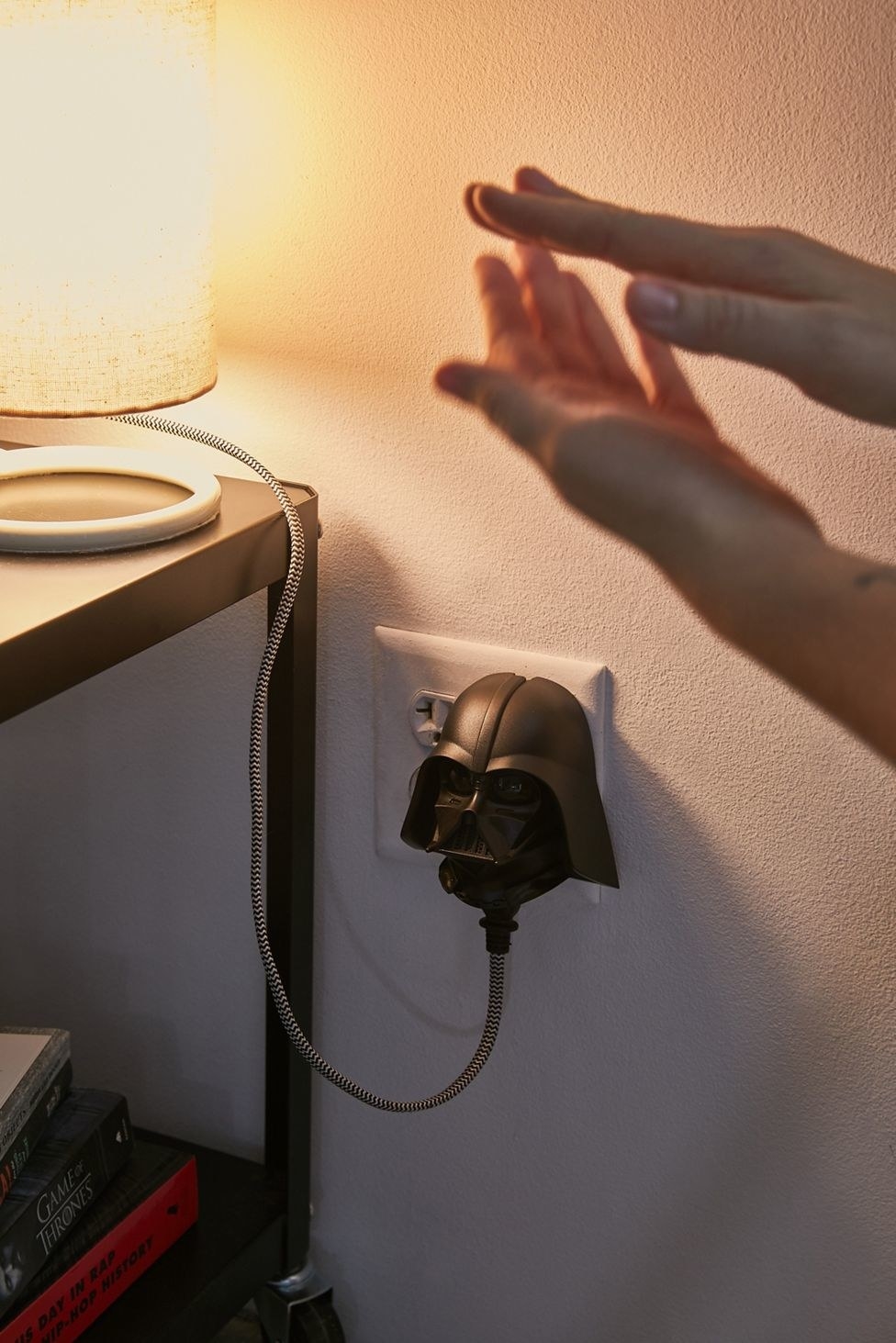 A person clapping their hands to control a voice-activated wall plug shaped like Darth Vader&#x27;s head