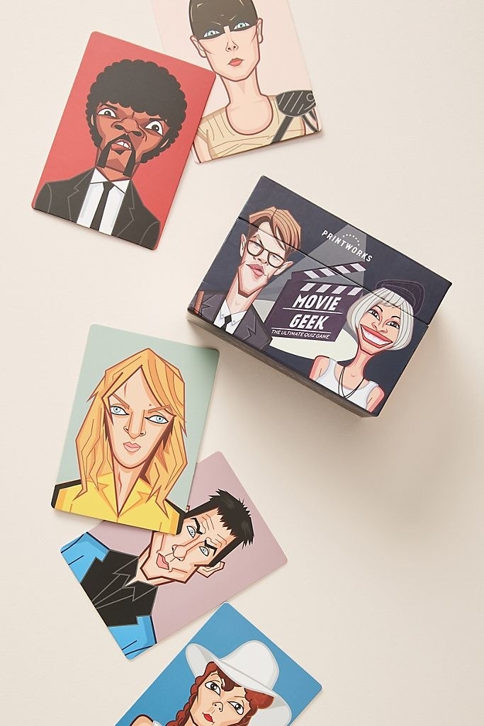 An illustrated movie trivia box with the game title "Movie Geek" laying on a beige background with loose cards outside of it, each featuring a stylized version of famous characters in hit movies