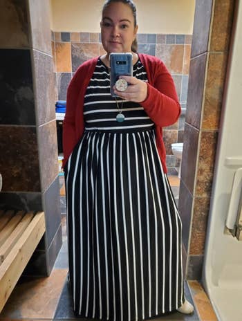 reviewer wearing a black and white-striped A-line maxi dress with horizontal stripes from the waist up and vertical stripes from the waist down 