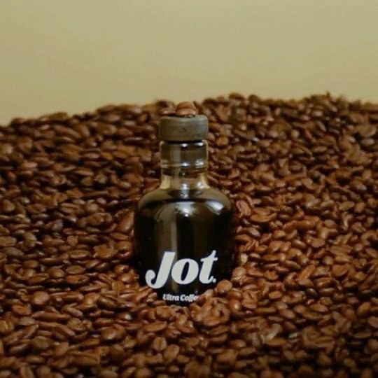 The screw-top bottle of coffee concentrate surrounded by coffee beans