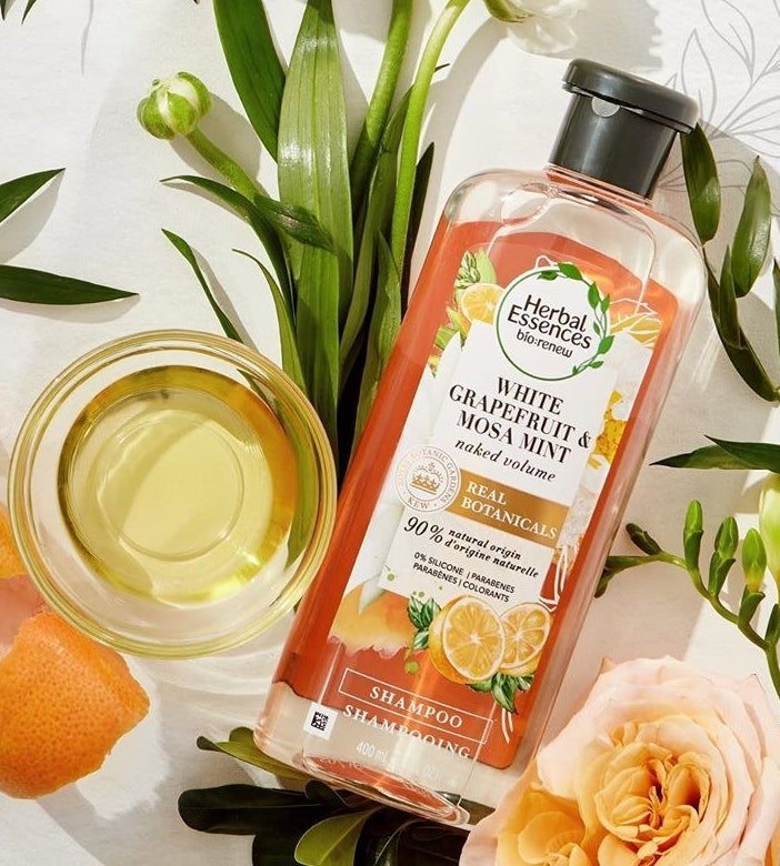an orange and clear plastic bottle with black cap labeled "Herbal Essences white grapefruit & mosa mint"