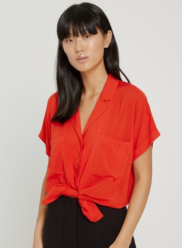 model in bright red button-up blouse with short sleeves, a collar, and a large pocket on each side of the chest