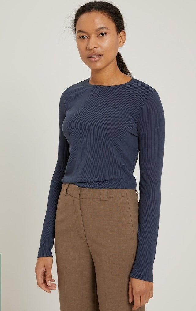 model in a navy long sleeve ribbed tee in navy tucked into brown trousers