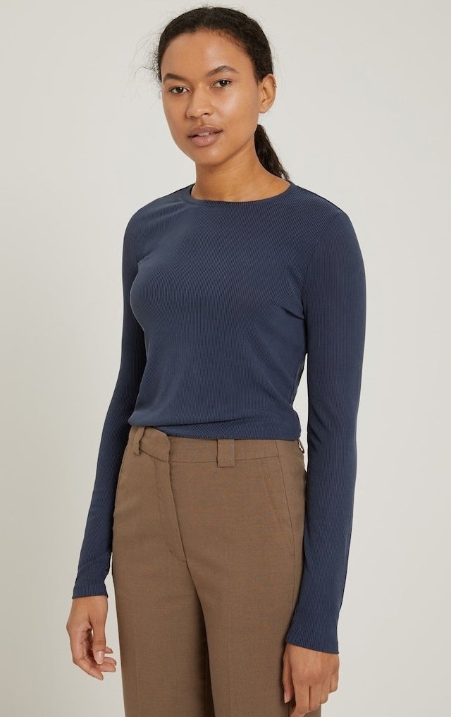 model in a navy long sleeve ribbed tee in navy tucked into brown trousers