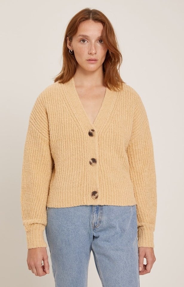 model in honey yellow v-neck ribbed cardigan with three large buttons styled with lgiht wash mom jeans