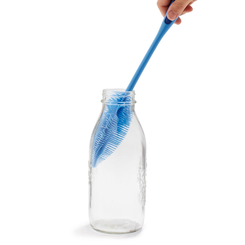 A hand using the blue brush with feather-like bristles to clean the inside of a glass bottle