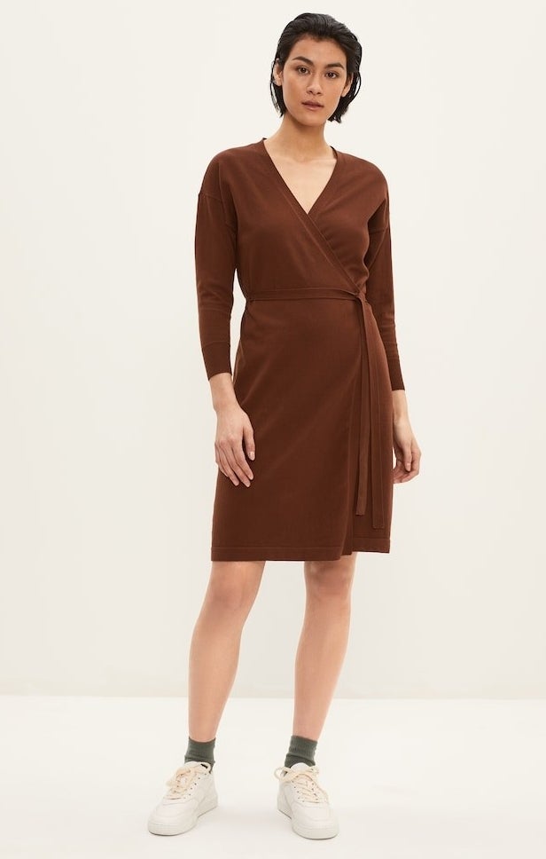 model in brown wrap dress with a v-neck waist tie and long sleeves, styled with with sneakers 