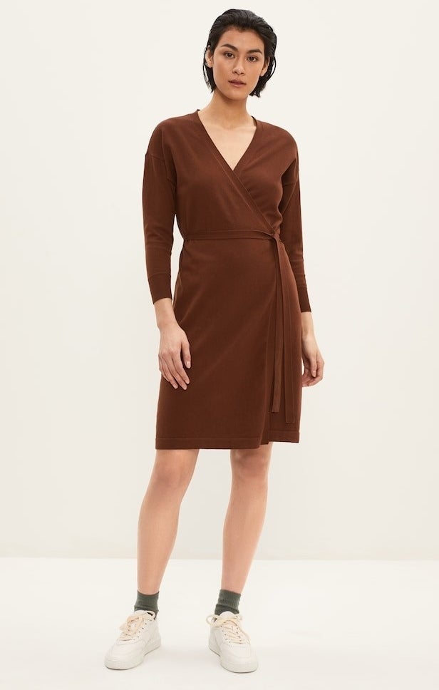 model in brown wrap dress with a v-neck waist tie and long sleeves, styled with with sneakers 