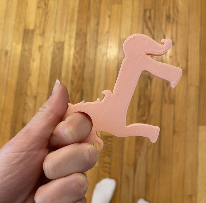 BuzzFeed editor Emma Lord holding a unicorn-shaped door opener with a hole to put your finger in and a hook to open doors