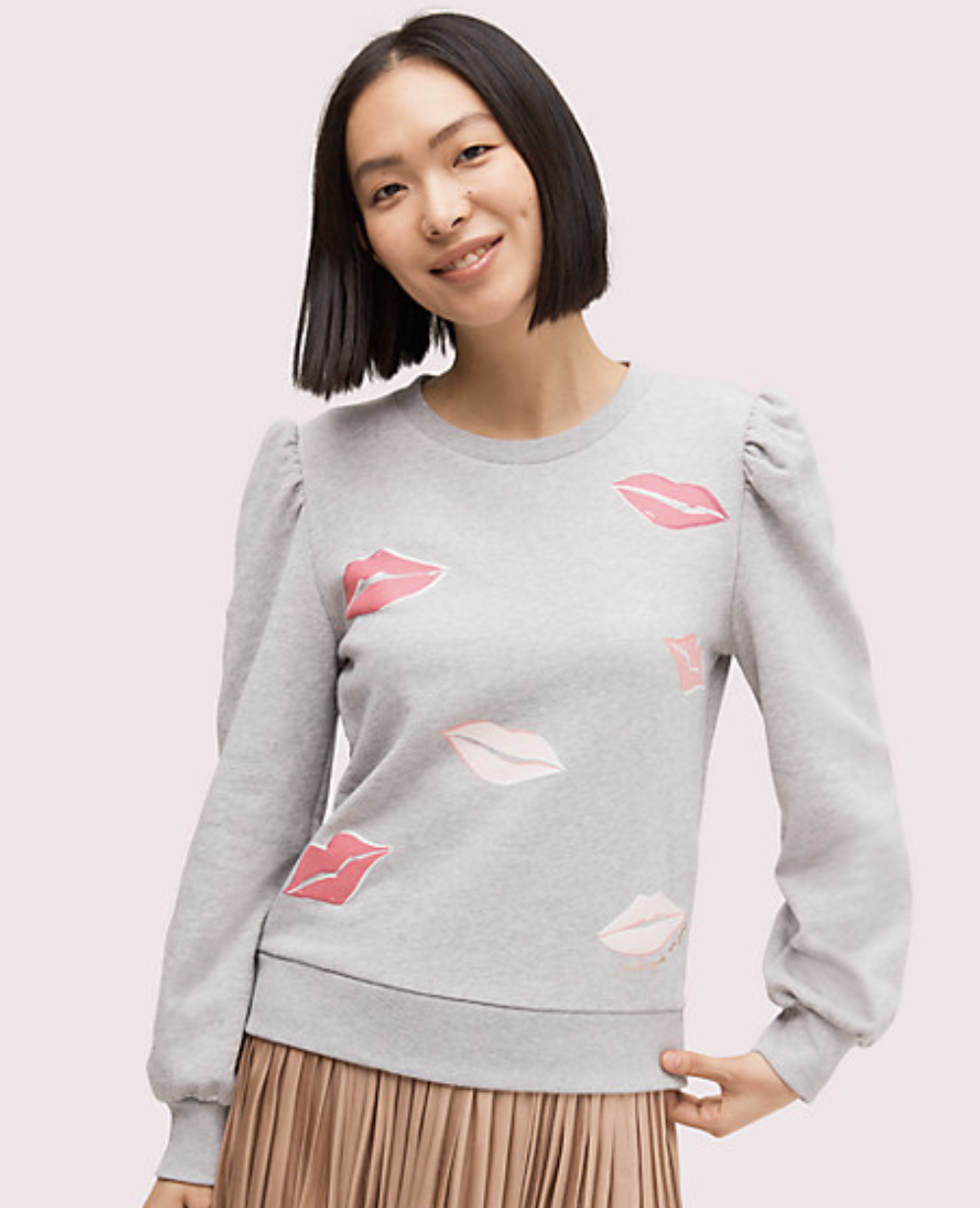 Model wearing grey sweatshirt with puff sleeves and different shades of pink lips around the bodice