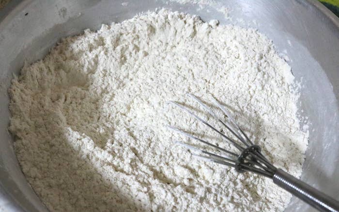 A medium shot of a bowl of flour and a whisk sticking out of the flour