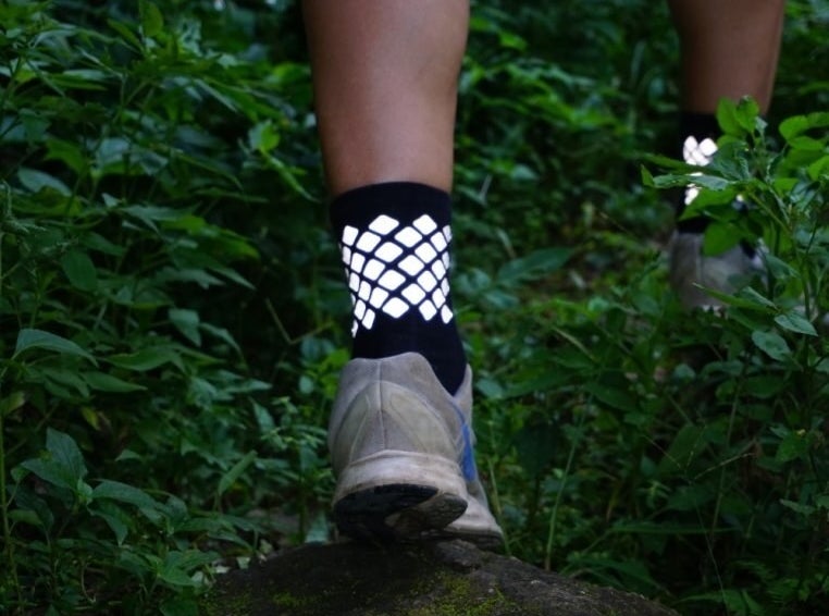A person wearing the reflective socks while walking on a leafy path