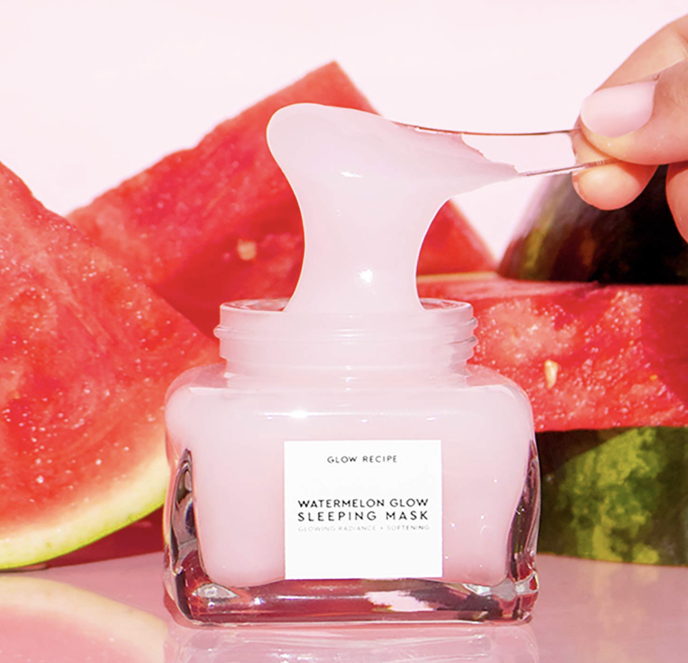 A bottle that says &quot;Glow Recipe Watermelon Glow Sleeping Mask&quot; with an applicator scooping a pink formula above it