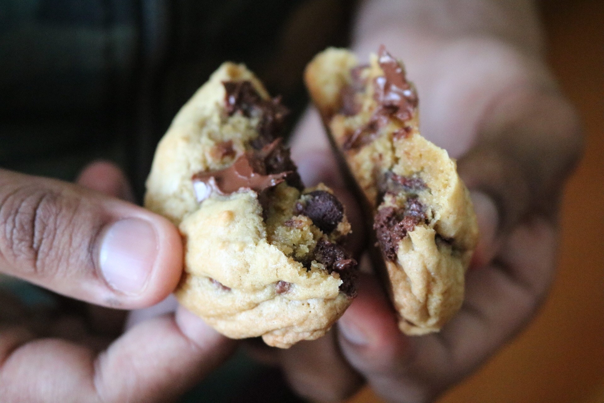 A cookie broken in half with chocolate chips inside and a gooey-looking melted chocolate chunk 