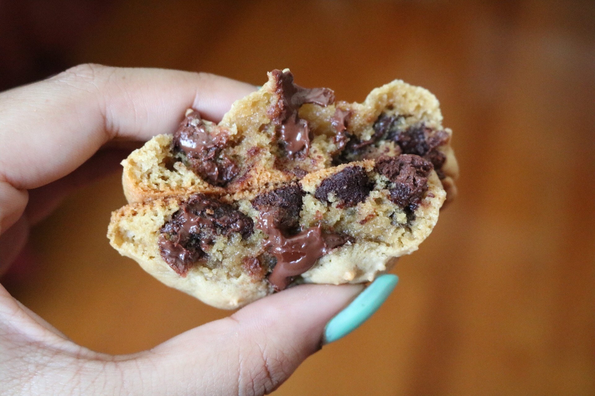 A close-up of a broken cookie with the halves stacked on top of one another to reveal the chocolate chips and the chewy texture