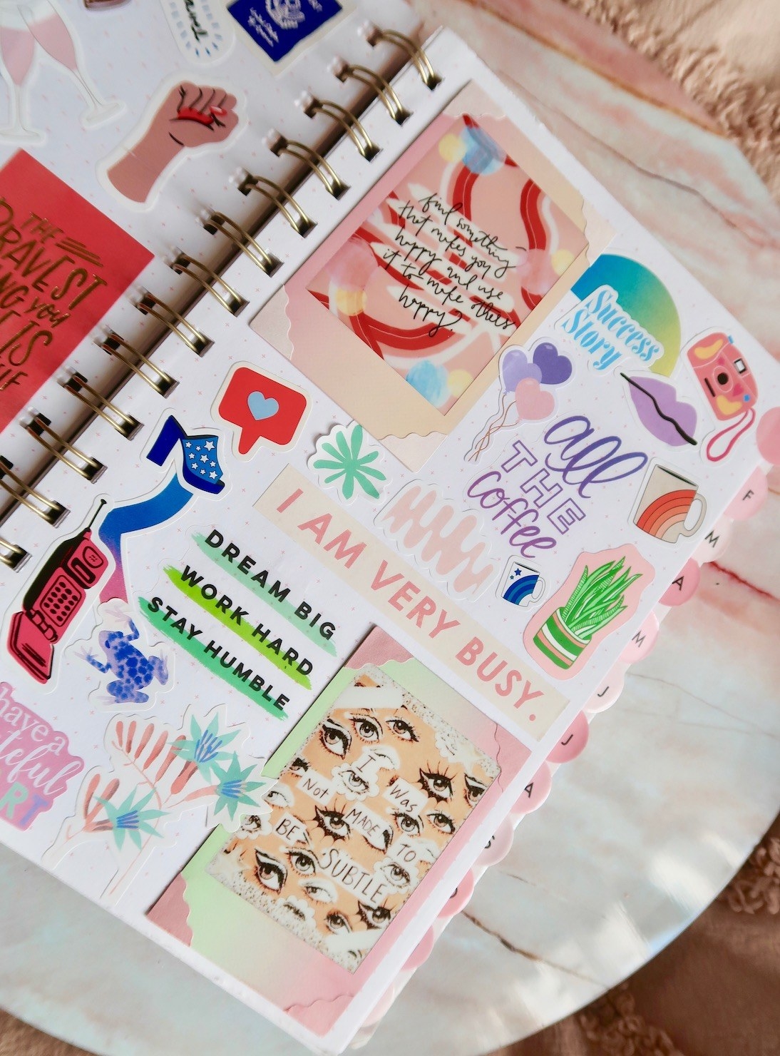 An open planner decorated with a lot of stickers and instant pictures taped inside