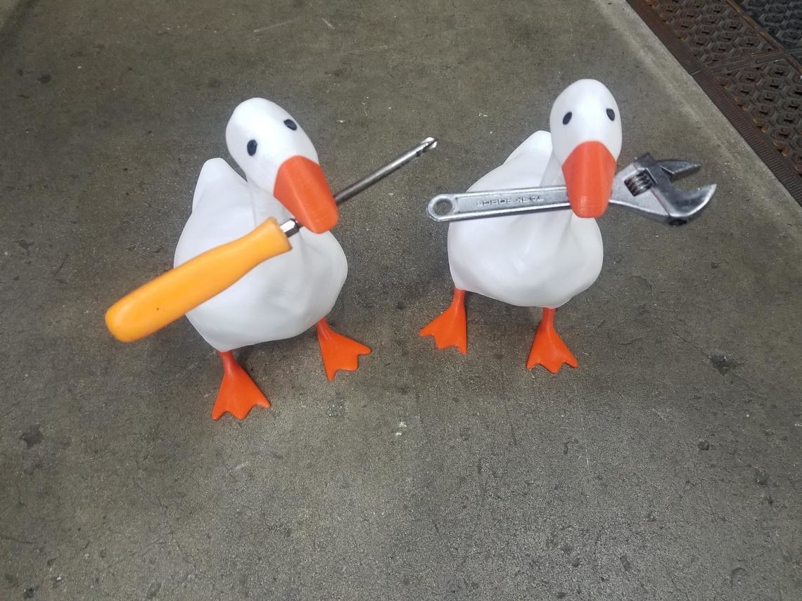 Two 3D printed white geese with a screwdriver and wrench held magnetically under each beak 