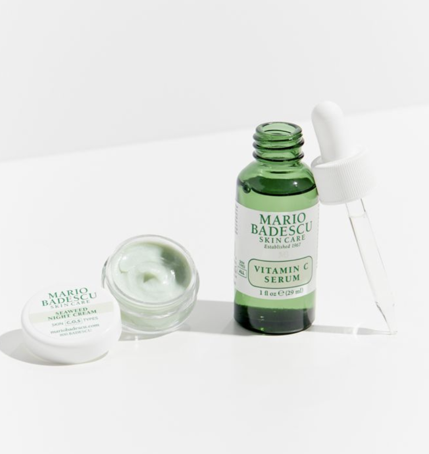 On the left, a circular bottle that says &quot;Mario Badescu Seaweed Night Cream&quot; filled with a green formula. On the right, a green bottle that says &quot;Mario Badescu Vitamin C Serum&quot; next to an applicator with clear liquid