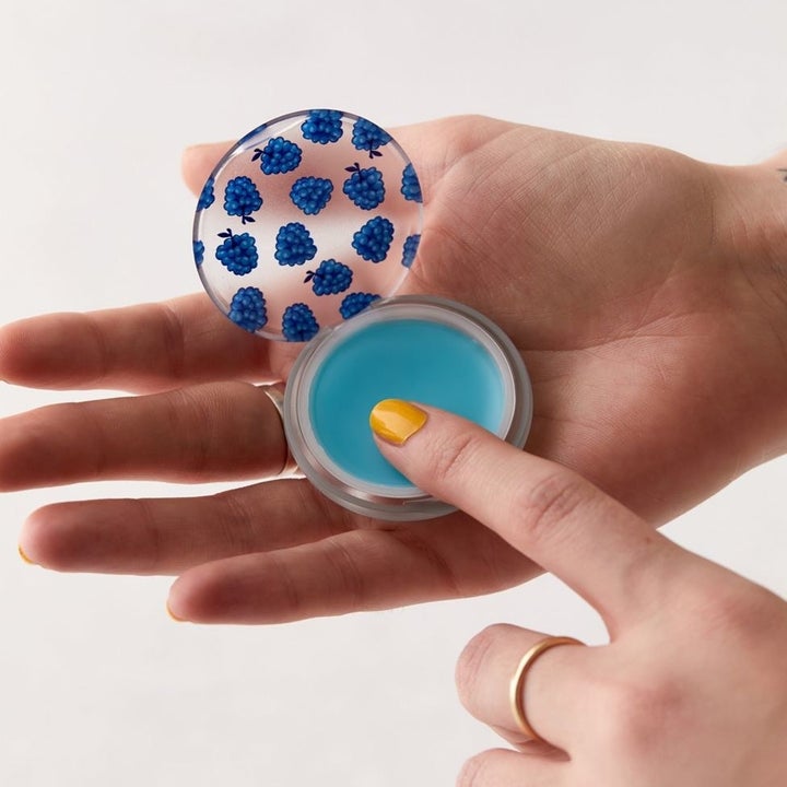 A person using the lip balm, which is removed from the PopSocket