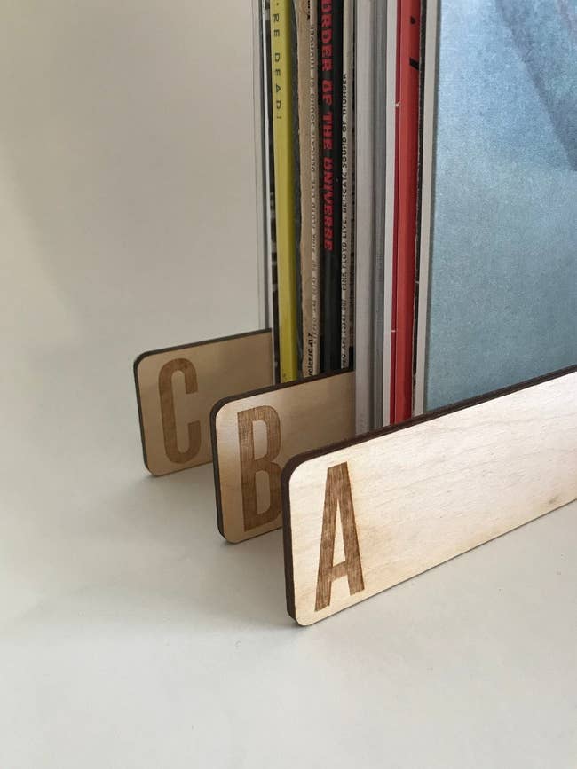 A stack of records with 3  woody  dividers with engraved letters connected  them 