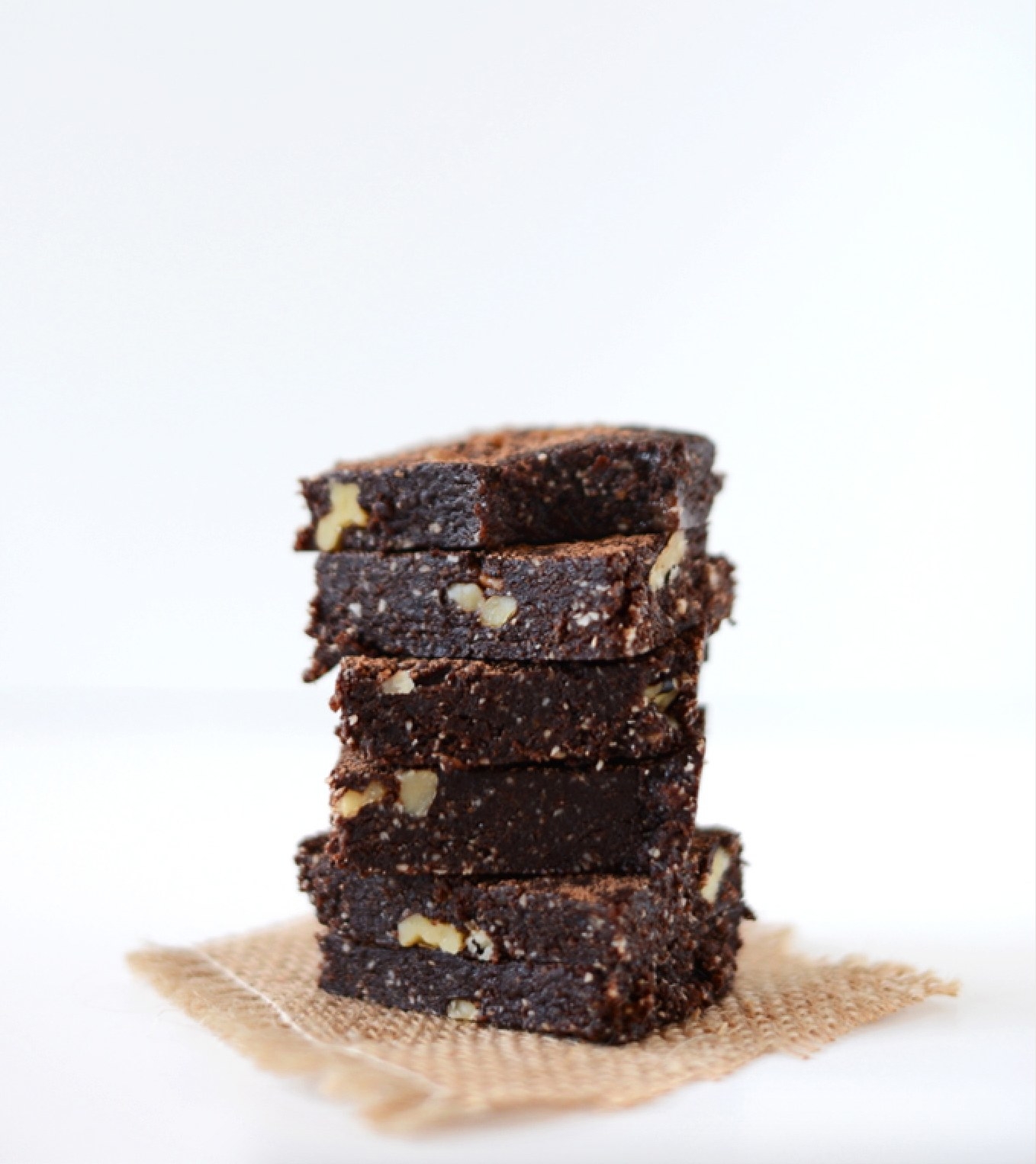 A stack of homemade brownies with visible walnut pieces, placed on a small burlap square
