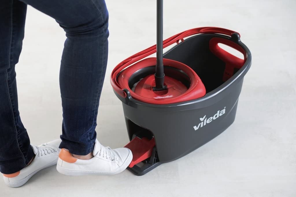 Foot pushing pedal on the back of a mop bucket