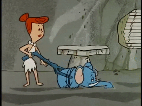 A gif of Wilma Flintstone using a small elephant attached to a branch to vacuum her home.