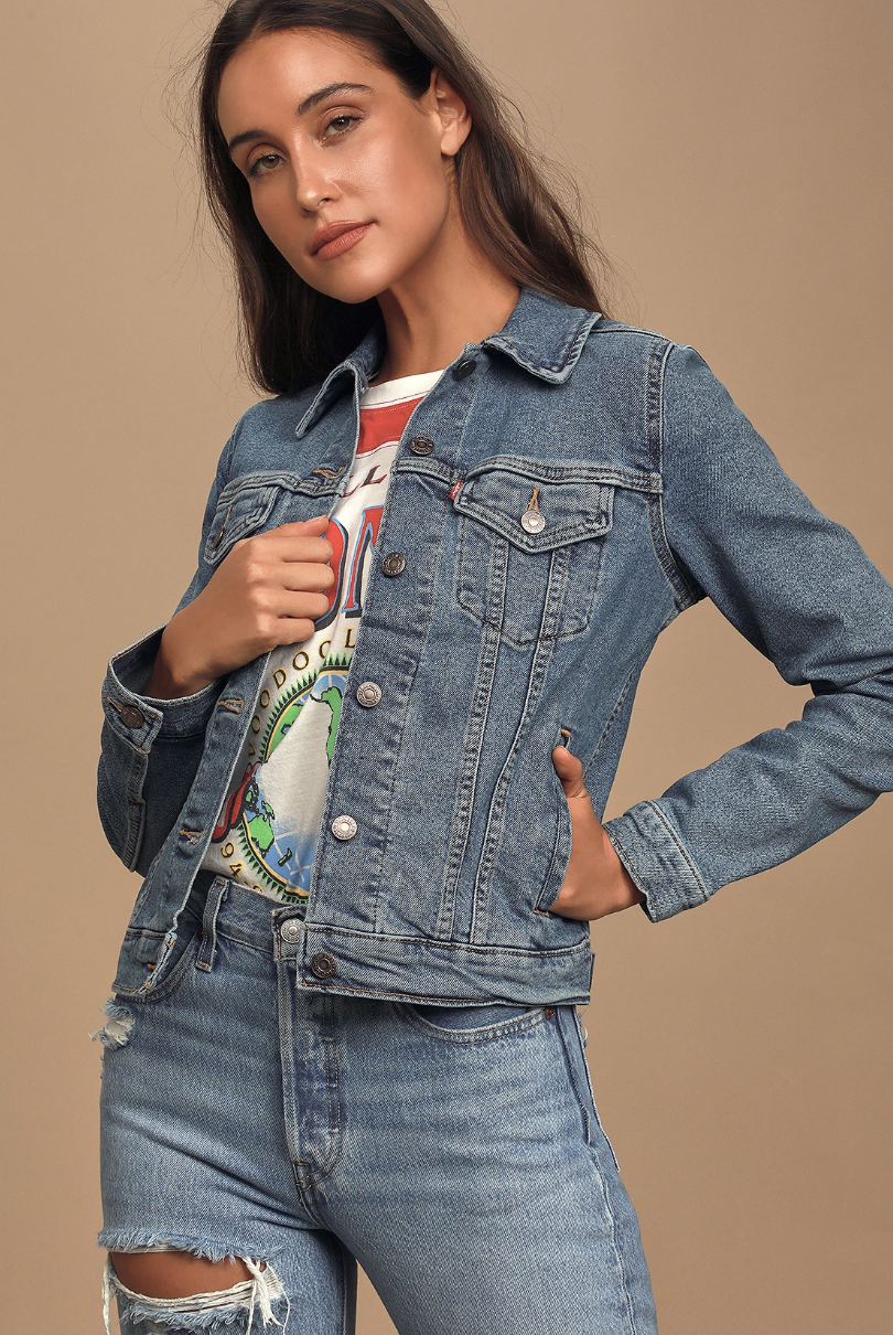 A model wearing a medium wash denim jacket over a shirt and jeans