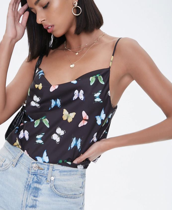 a person wearing a black cowl neck tank top with spaghetti straps and a design of various butterflies all over it