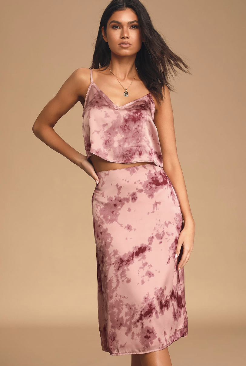 A model wearing a pink tie-dye midi skirt that falls just below her knee and a cropped cami to match