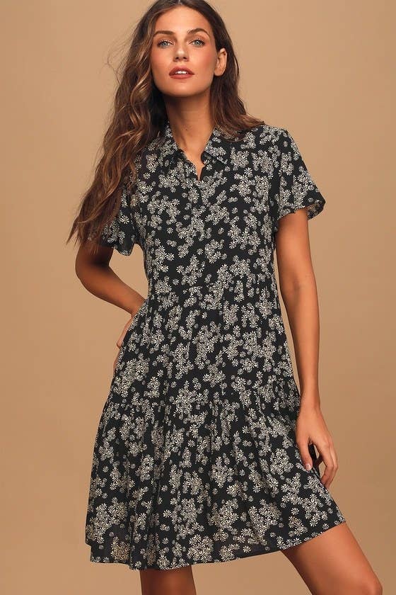 Model wearing black tiered short-sleeved shirtdress with small white floral design
