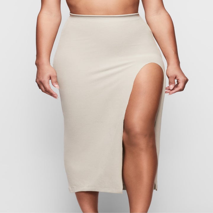 same model wearing a skirt with a high slit on one side to show the shapewear is undetectable beneath the garment