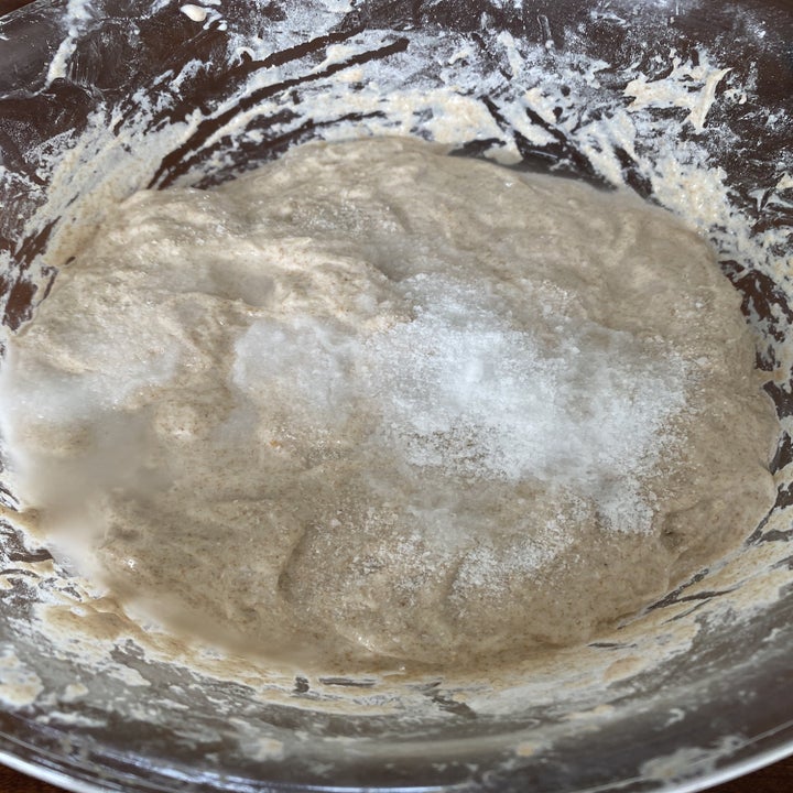 Salt and water sprinkled over dough in a mixing bowl.