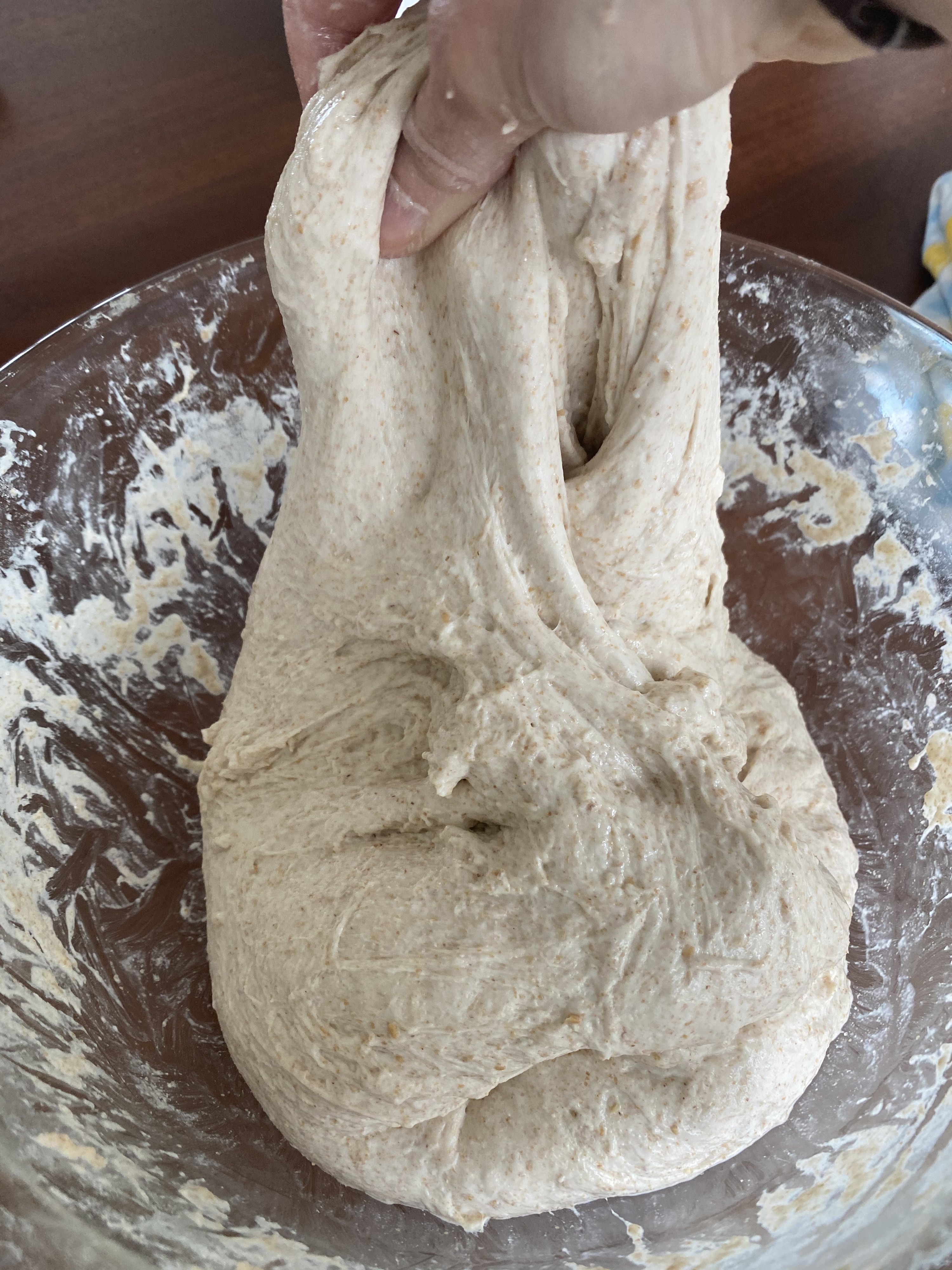 Hands stretching the dough upward while performing stretch and folds.