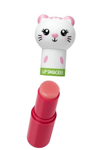 A cat face version of the tube opened to show that the animal head cap pops off to reveal a round, flat, pink lip balm bullet