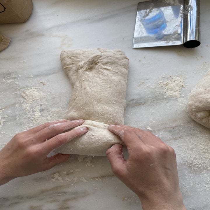 Hands rolling dough upwards into a spiral shape.