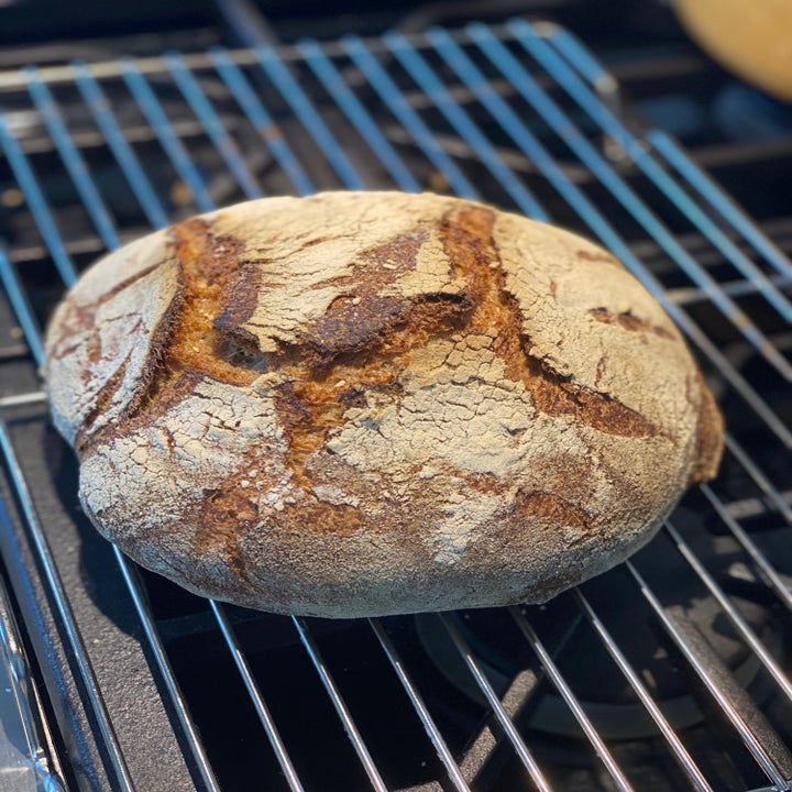A freshly baked load of bread cooling on a baking rack.