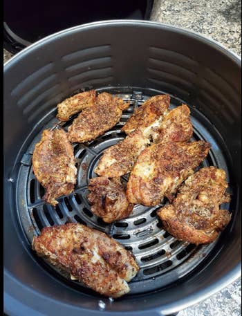 Open air fryer shelf showing fully cooked and seasoned chicken wings 