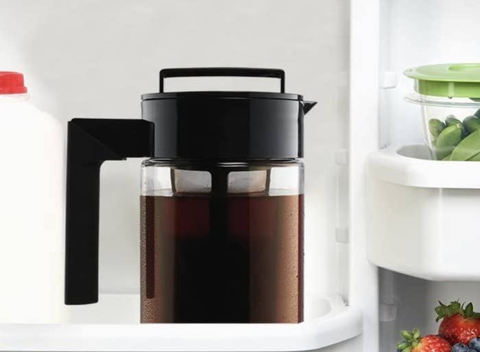 A pitcher with a coffee filter and a large handle, full of iced coffee in a fridge