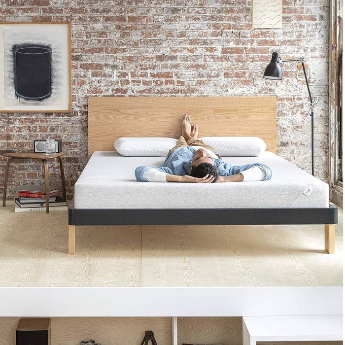 The Nod Adaptive Foam mattress staged in a room with a model reclining on top