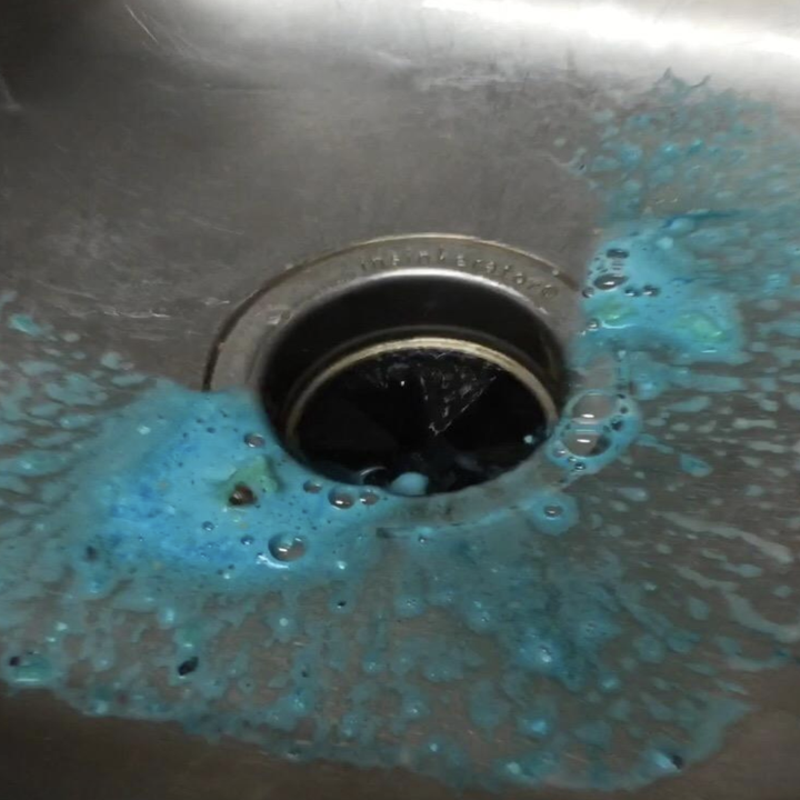 sink drain with blue liquid around it 