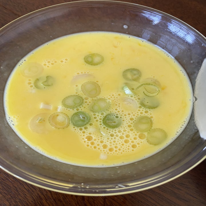 Scrambled eggs in a bowl with chopped scallions.