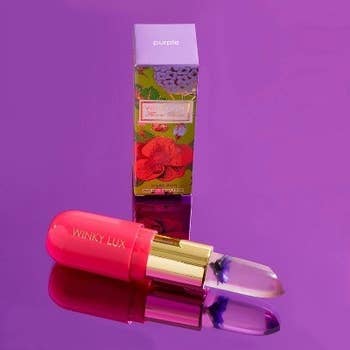 A tube of the purple flower version. The tube is oval-shaped and pink and gold