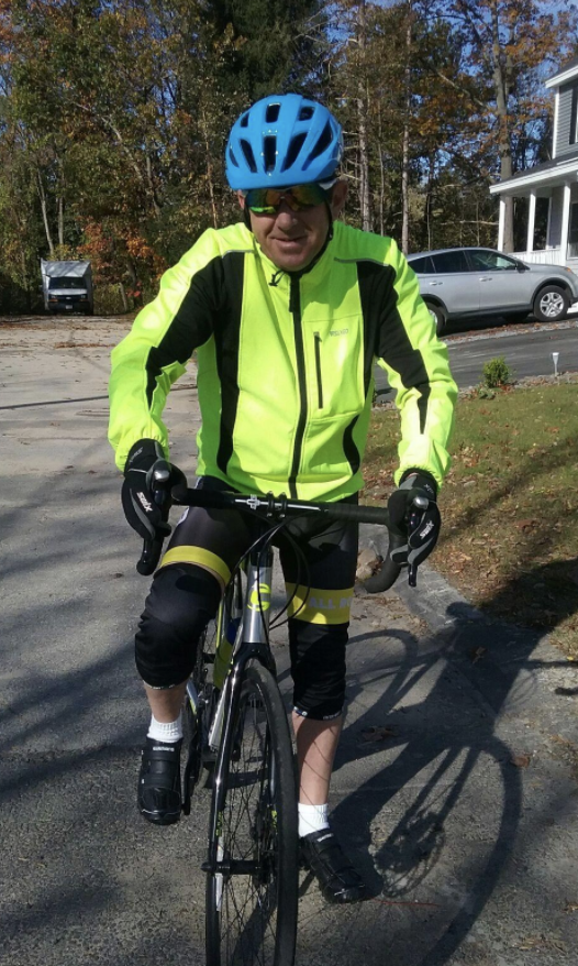 A reviewer wears a neon yellow reflective jacket while bike riding on a street