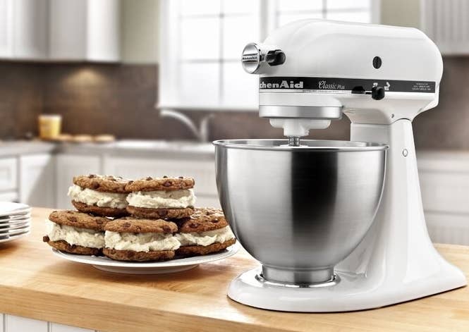 A white KitchenAid stand mixer next to a plate of baked treats