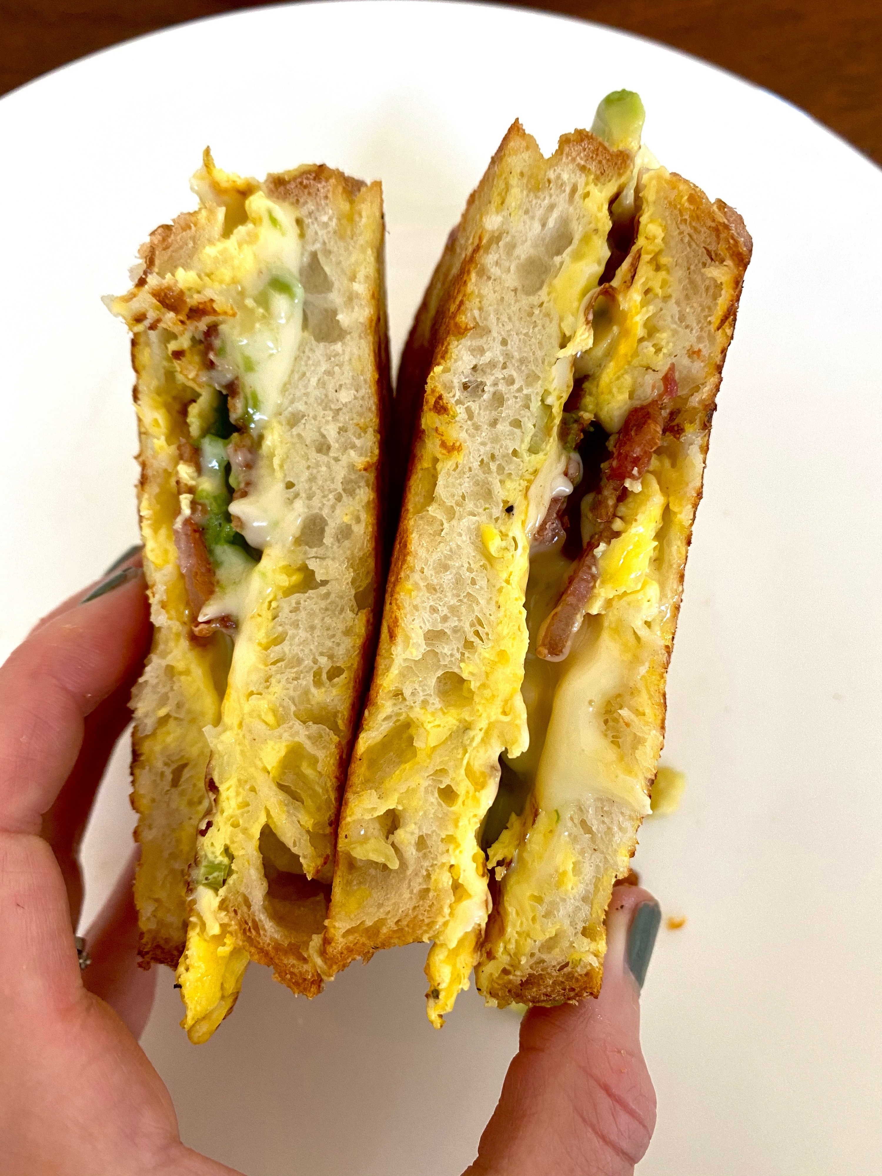 A cheesy breakfast sandwich sliced in half.