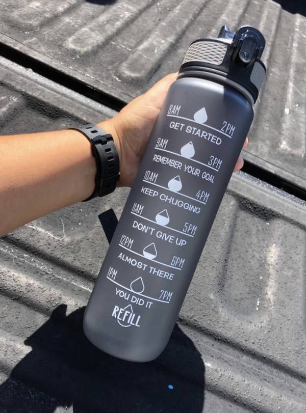A reviewer holds a gray time-marked water bottle 
