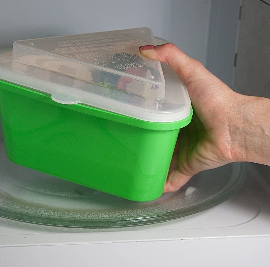 hand holding green steamer with clear plastic cover 