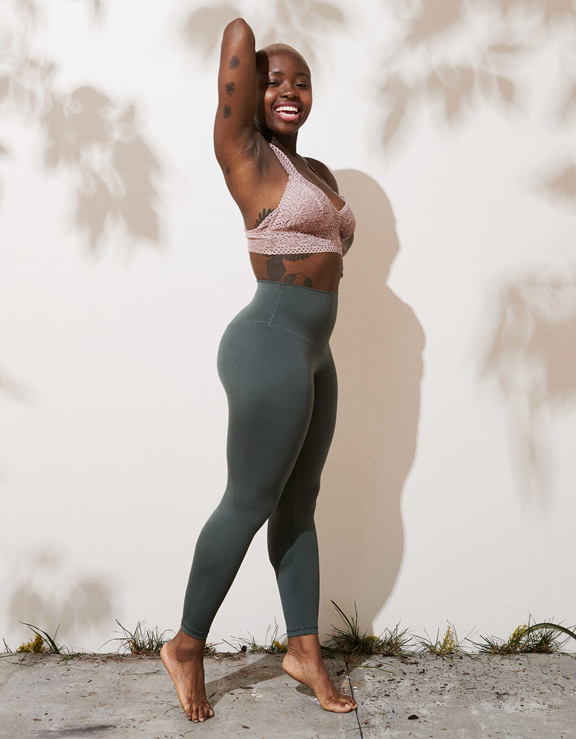 model posing on tip-toe in dark sage leggings that go up to the rib cage