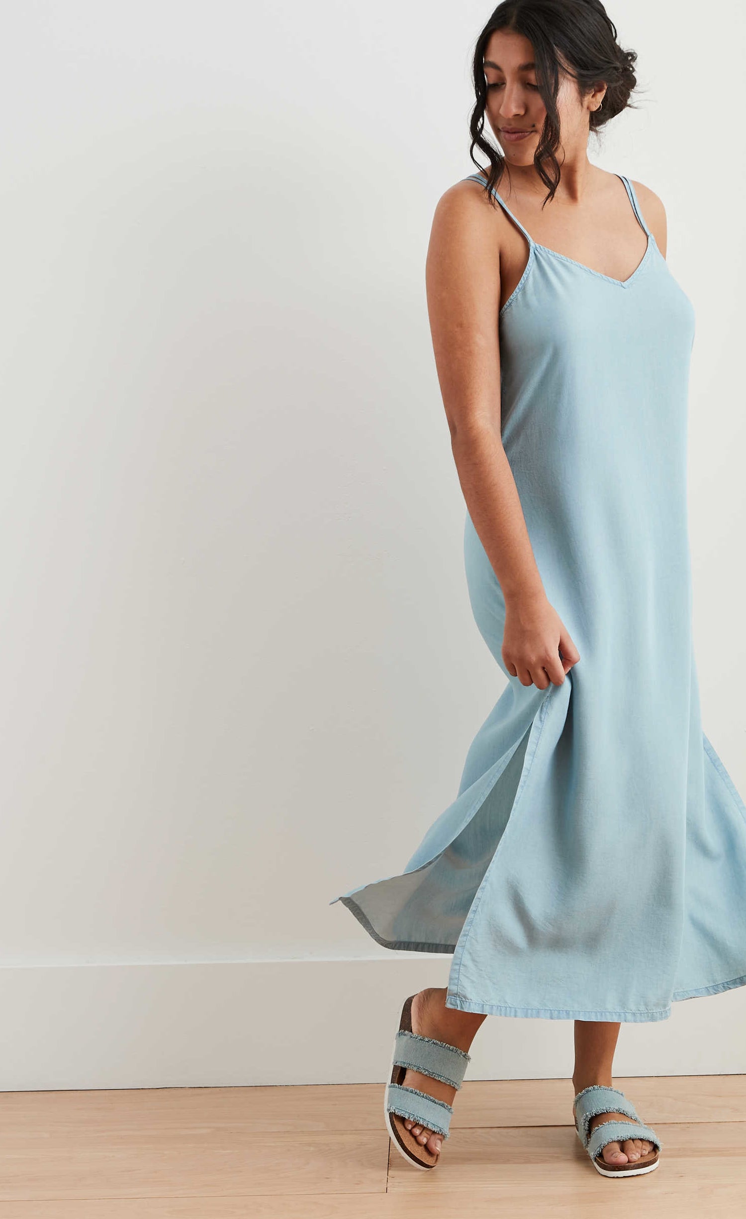 model in midi length chambray slip dress with spaghetti straps and slits up to the knee on either side